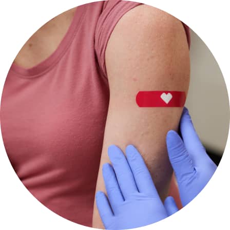 A practitioner applying a CVS bandage to a patient’s upper arm vaccination site.
