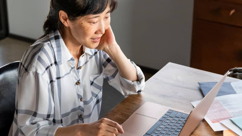 A person looking at their laptop screen while paying bills.