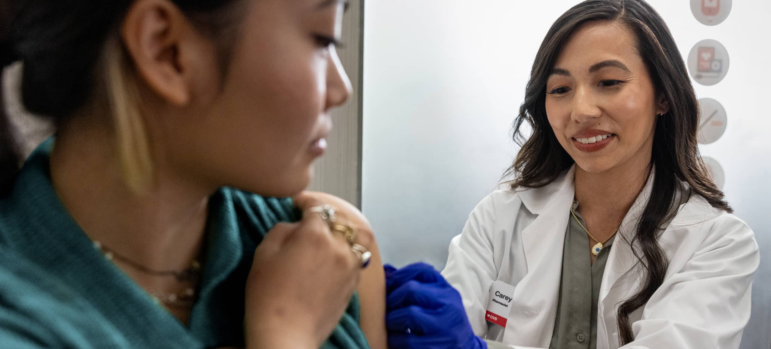 A CVS practitioner applying a bandage to a patient's upper arm.